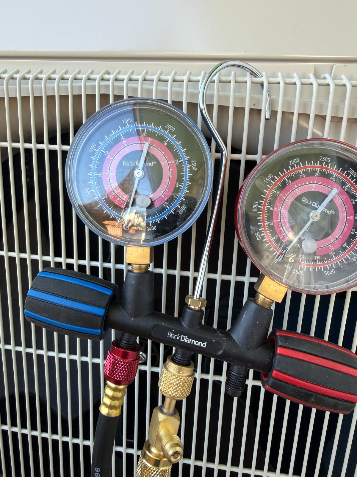 Refrigerant gauges connected to an outdoor air conditioning unit during a service