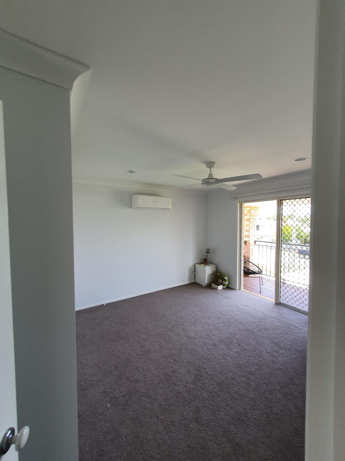 Split-system air conditioner installed in a living room with balcony access