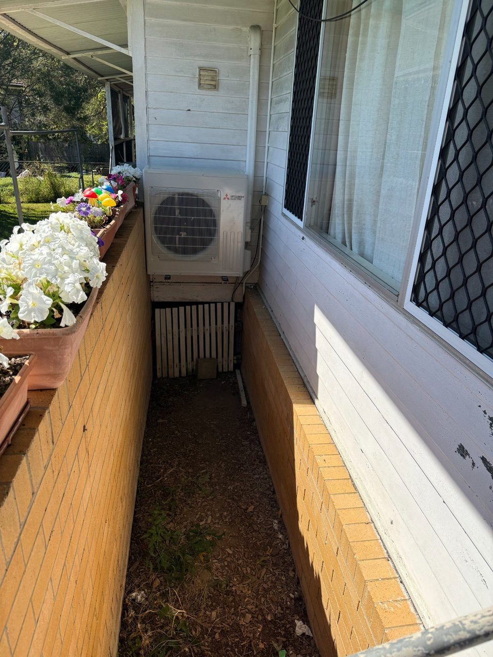 Split-system outdoor unit installed along the narrow side path of a home