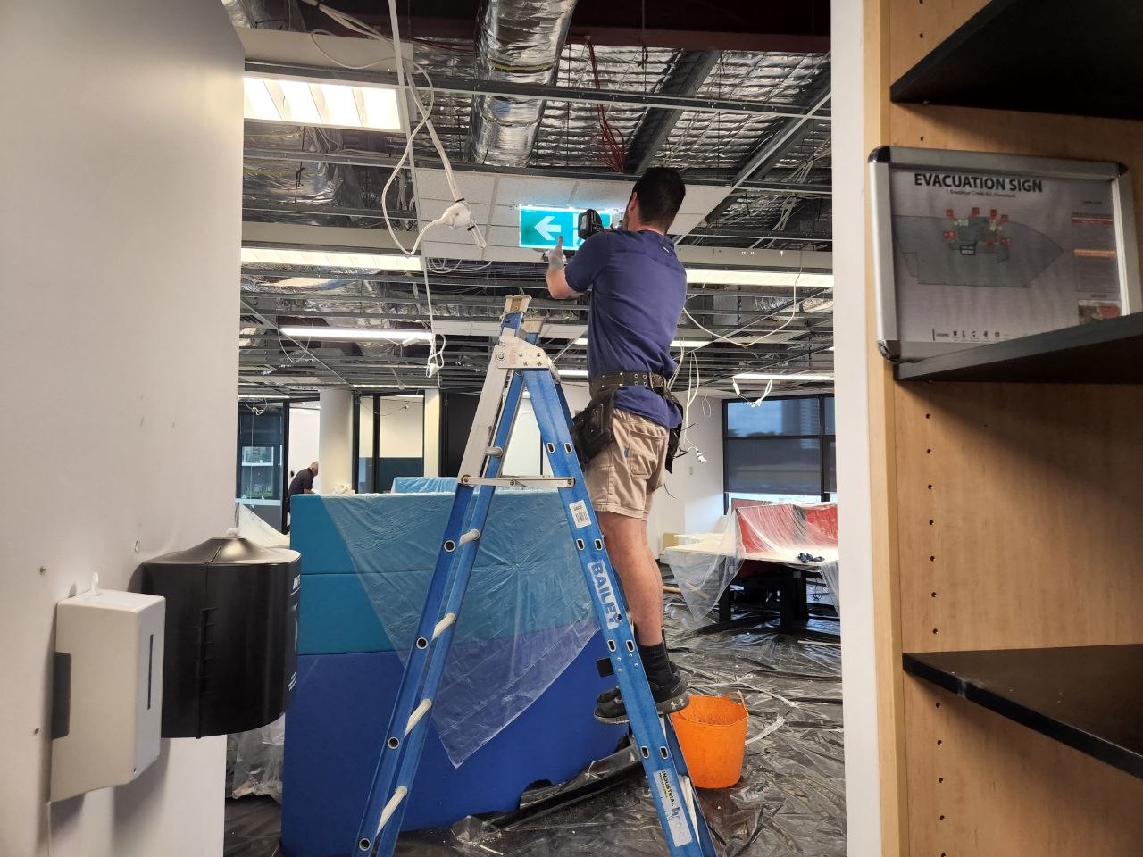 Electrician installing ceiling wiring during a commercial office fit-out