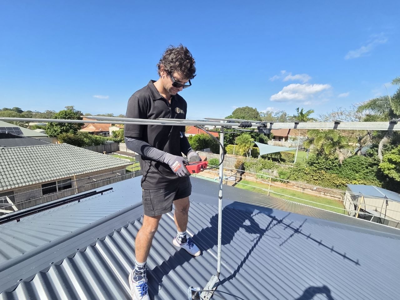 Electrician installing conduit on a roof on Brisbane's north side