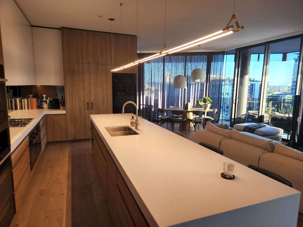 Modern kitchen lit by pendant lights and a linear LED pendant over the island