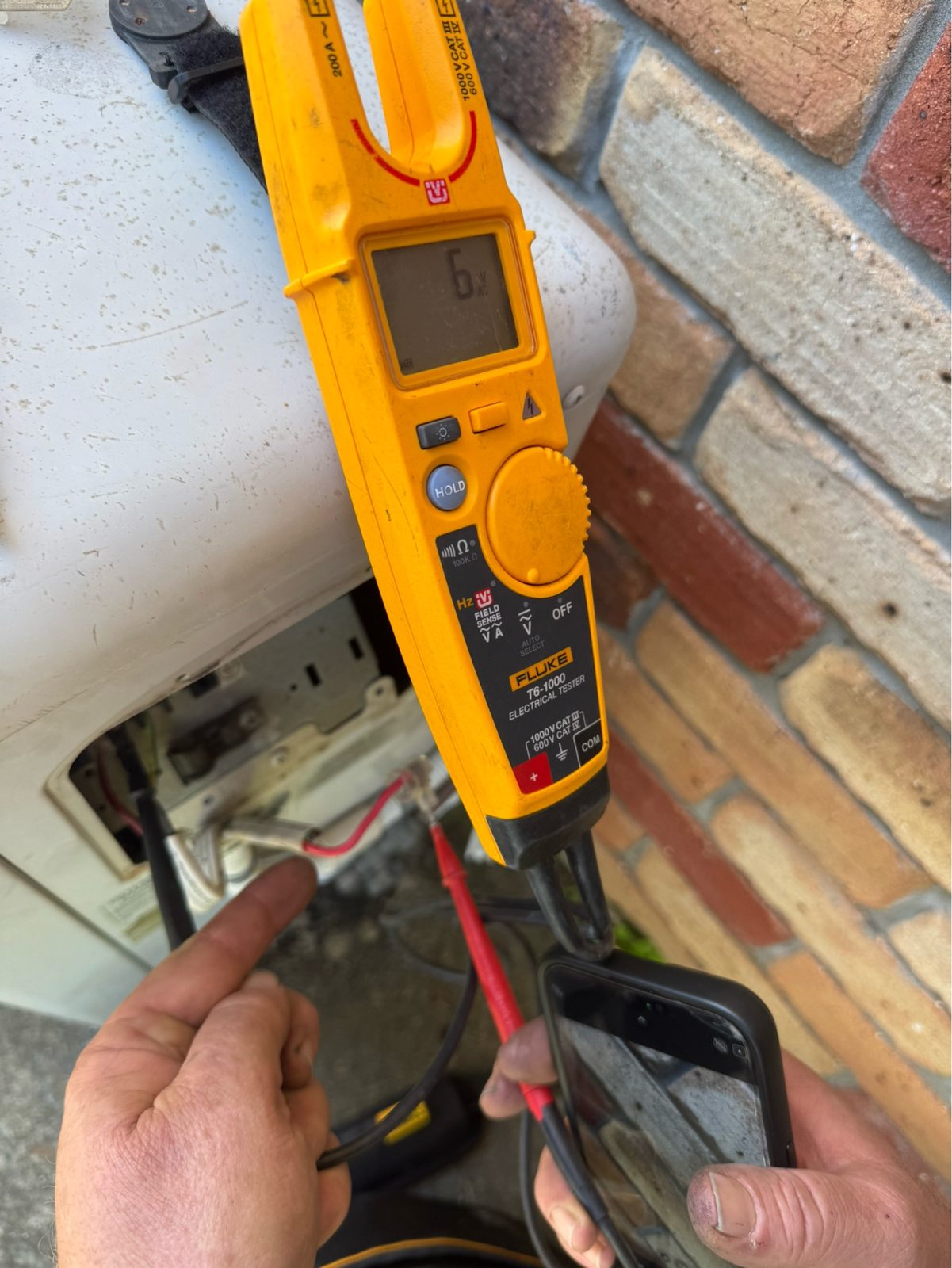Electrician testing wiring with a multimeter during an insurance assessment