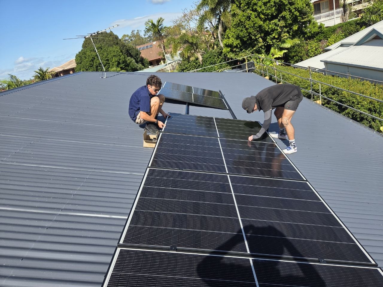 Two Elkins Electrical installers fitting solar panels to a metal roof