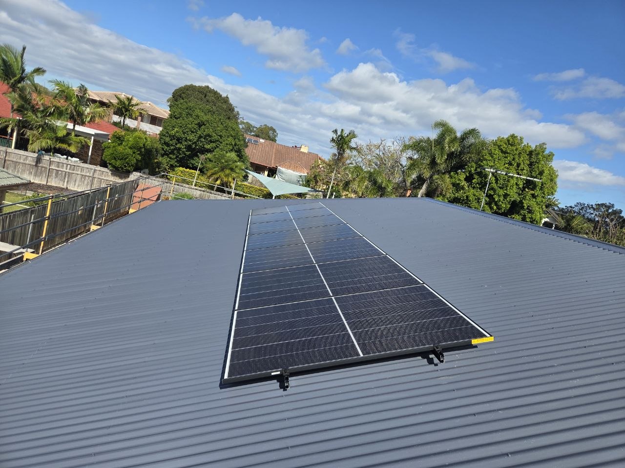 Completed solar panel array on a corrugated metal roof in suburban Brisbane