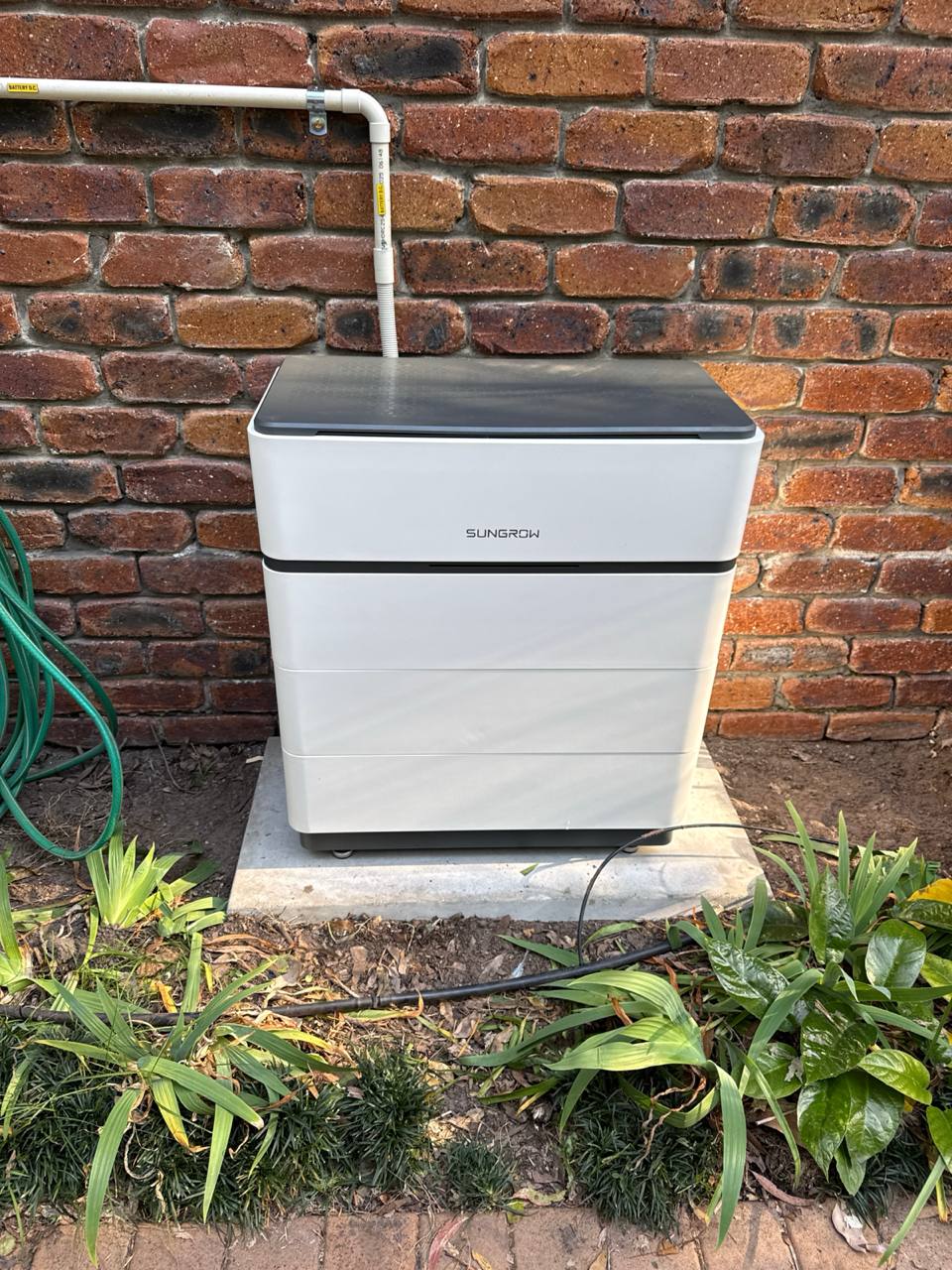 Home battery storage unit installed against a brick wall